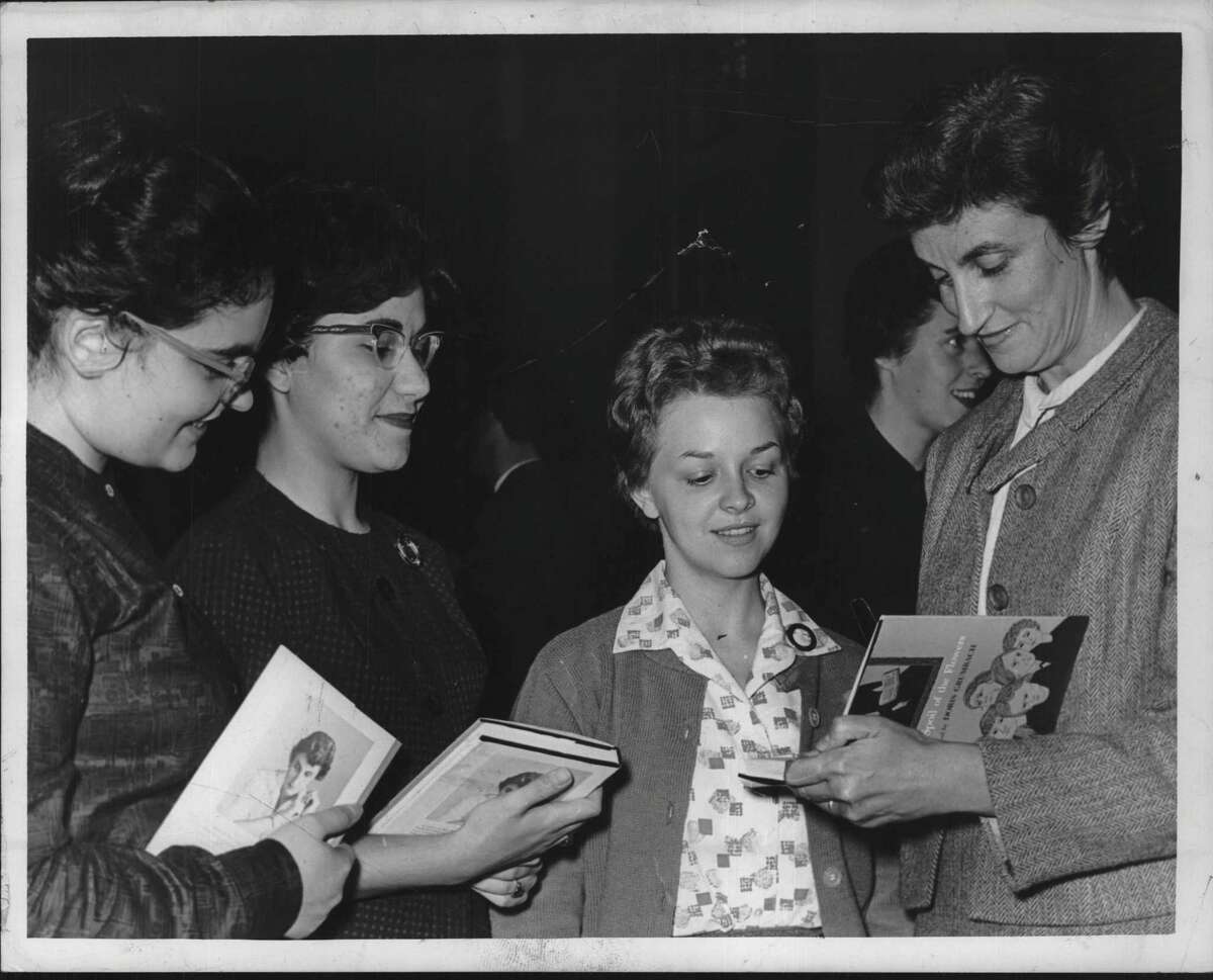 Doris Grumbach, right, autographs copy of her novel "The Spoil of Flowers" in 1962 at an event in Albany. Grumbach, a scholar of medieval and modern literature, taught at the College of Saint Rose from 1960 to 1971. She died Nov. 4, 2022, at age 104. . Via Times Union Historic Images